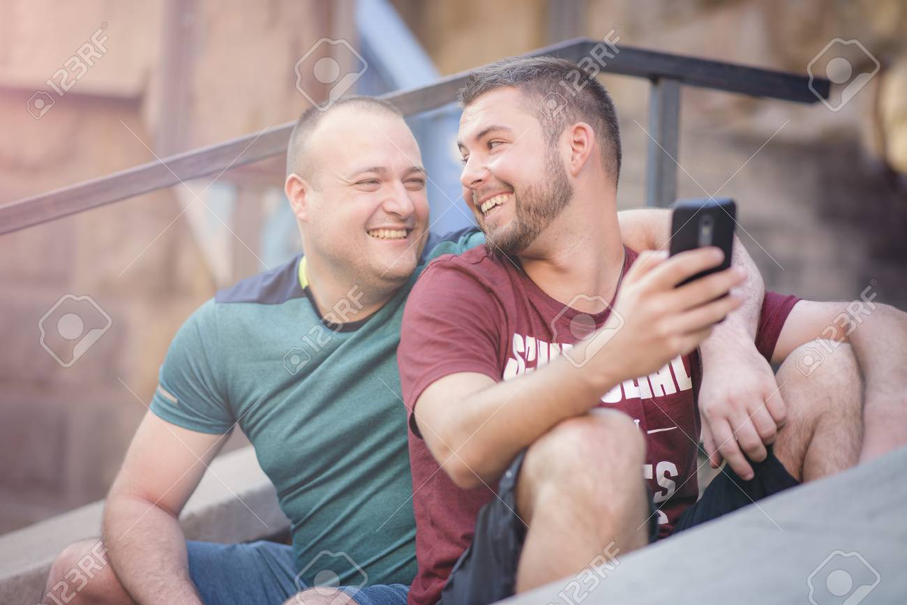 Cute Gay Couple Chatting About Online Content On Their Phone Stock Photo 96032512 Cute Gay Couple Chatting About Online Content On Their Phone Stock Photo 96032512