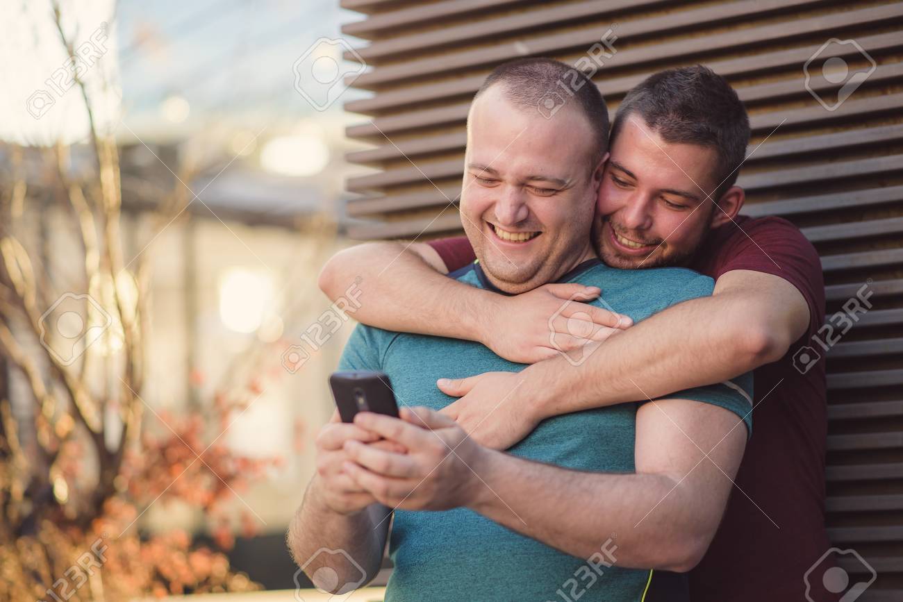 Cute Gay Couple Chatting About Online Content On Their Phone Stock Photo 96571372 Cute Gay Couple Chatting About Online Content On Their Phone Stock Photo 96571372