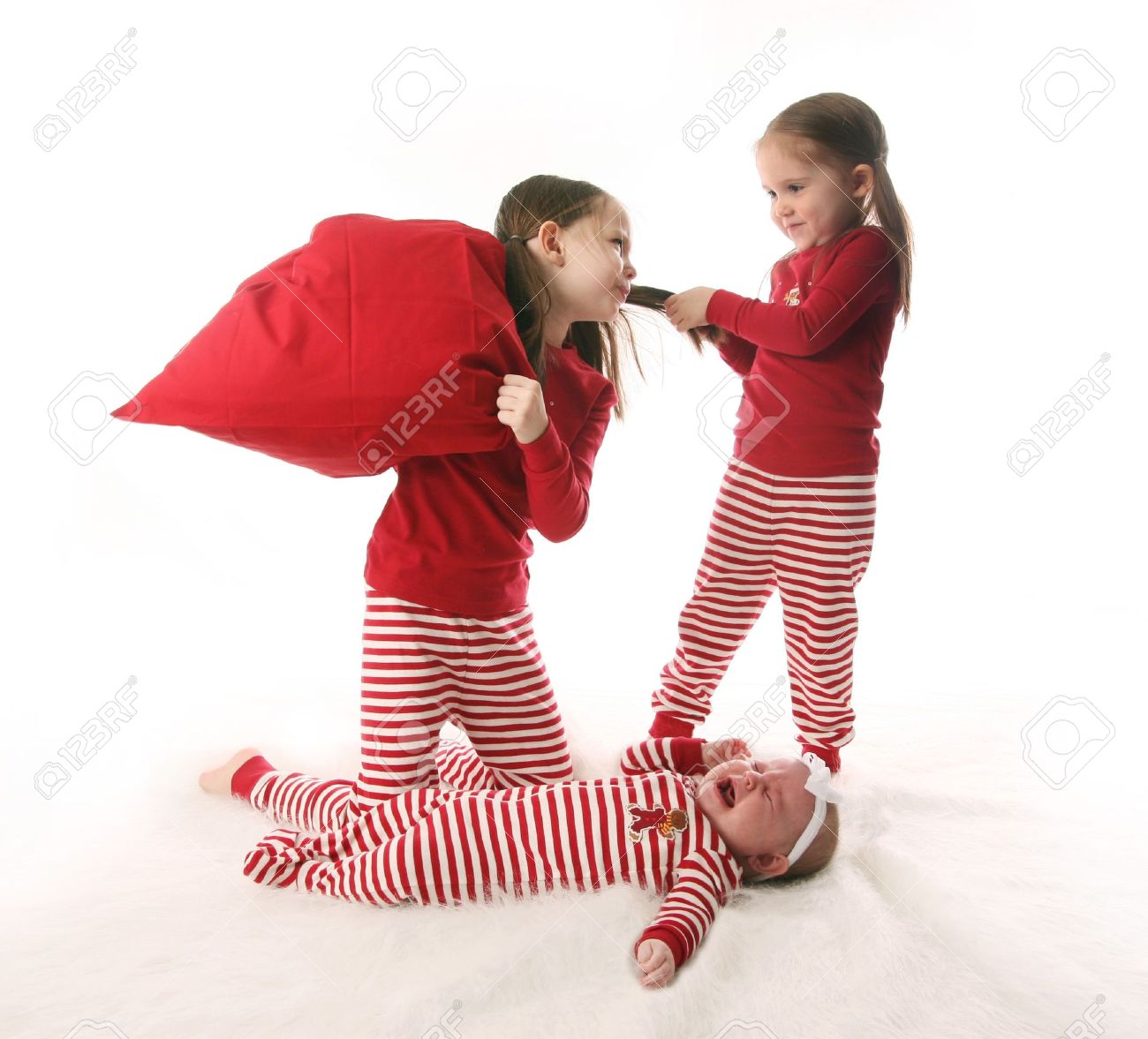 Three Sisters Dressed In Christmas Pajamas. Two Older Girls Are Pulling  Hair And Having A Pillow Fight While The Baby Is Crying. Stock Photo,  Picture and Royalty Free Image. Image 8383218., image size:1300x1177
