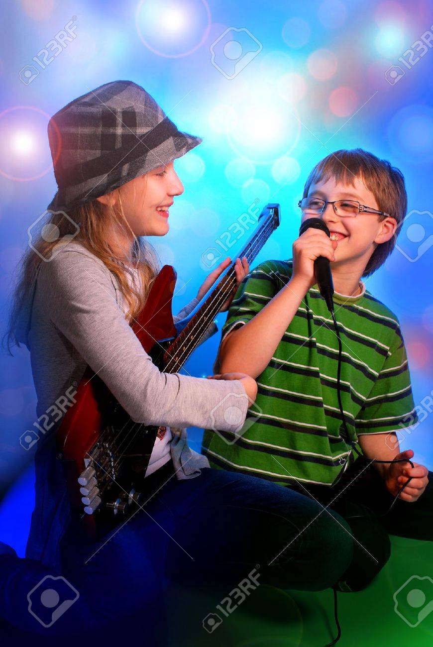 young girl playing the bass guitar and boy singing with microphone on stage - 19428858 young girl playing the bass guitar and boy singing with microphone on stage - 19428858