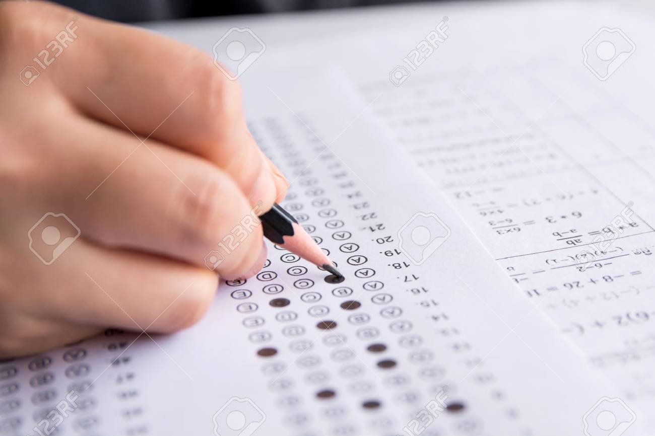 Students hand holding pencil writing selected choice on answer sheets and Mathematics question sheets. students testing doing examination. school exam - 105015355 Students hand holding pencil writing selected choice on answer sheets and Mathematics question sheets. students testing doing examination. school exam - 105015355