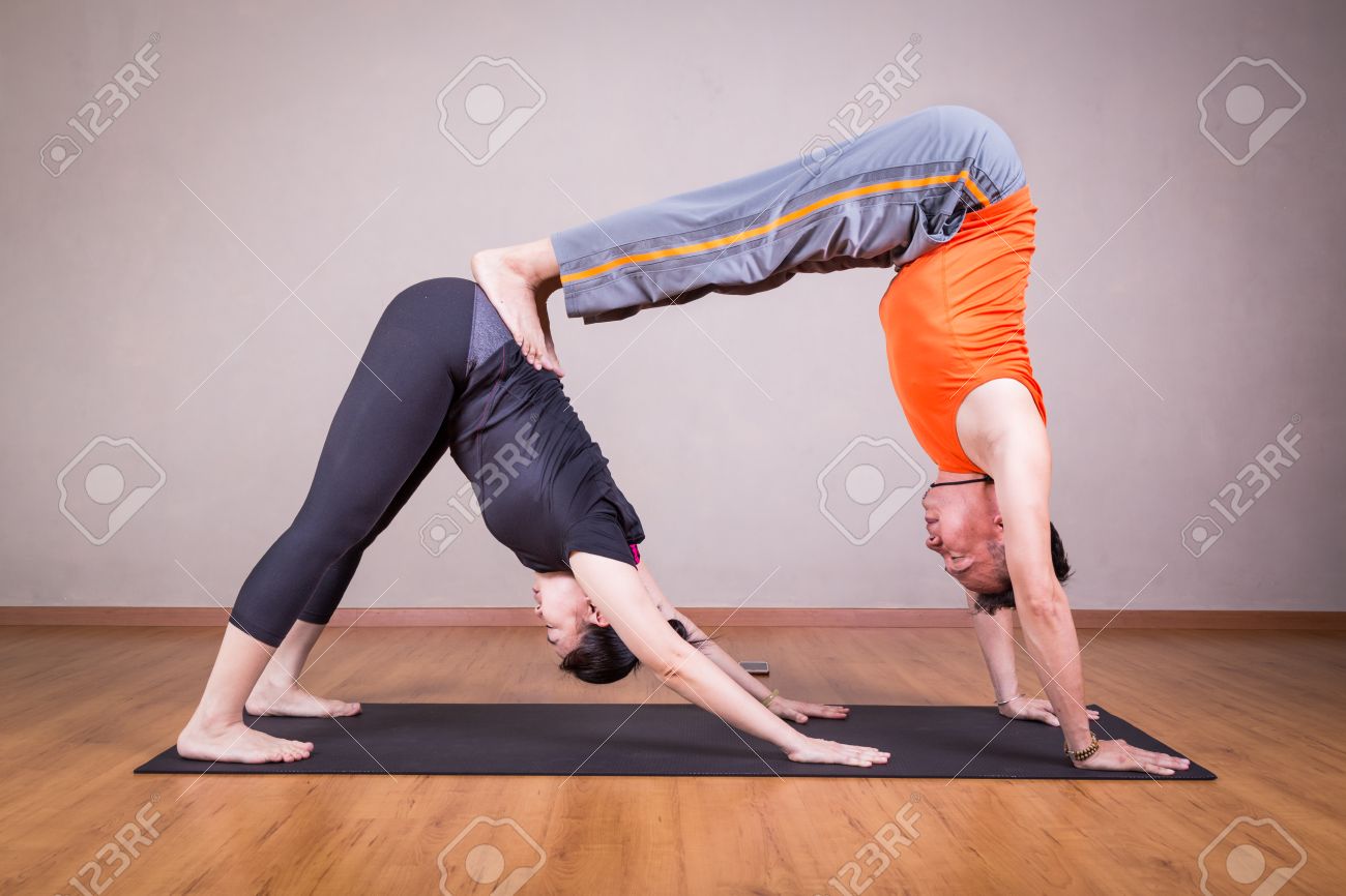 Partner yoga pose of double downward dog by a couple within a.. Partner yoga pose of double downward dog by a couple within a..