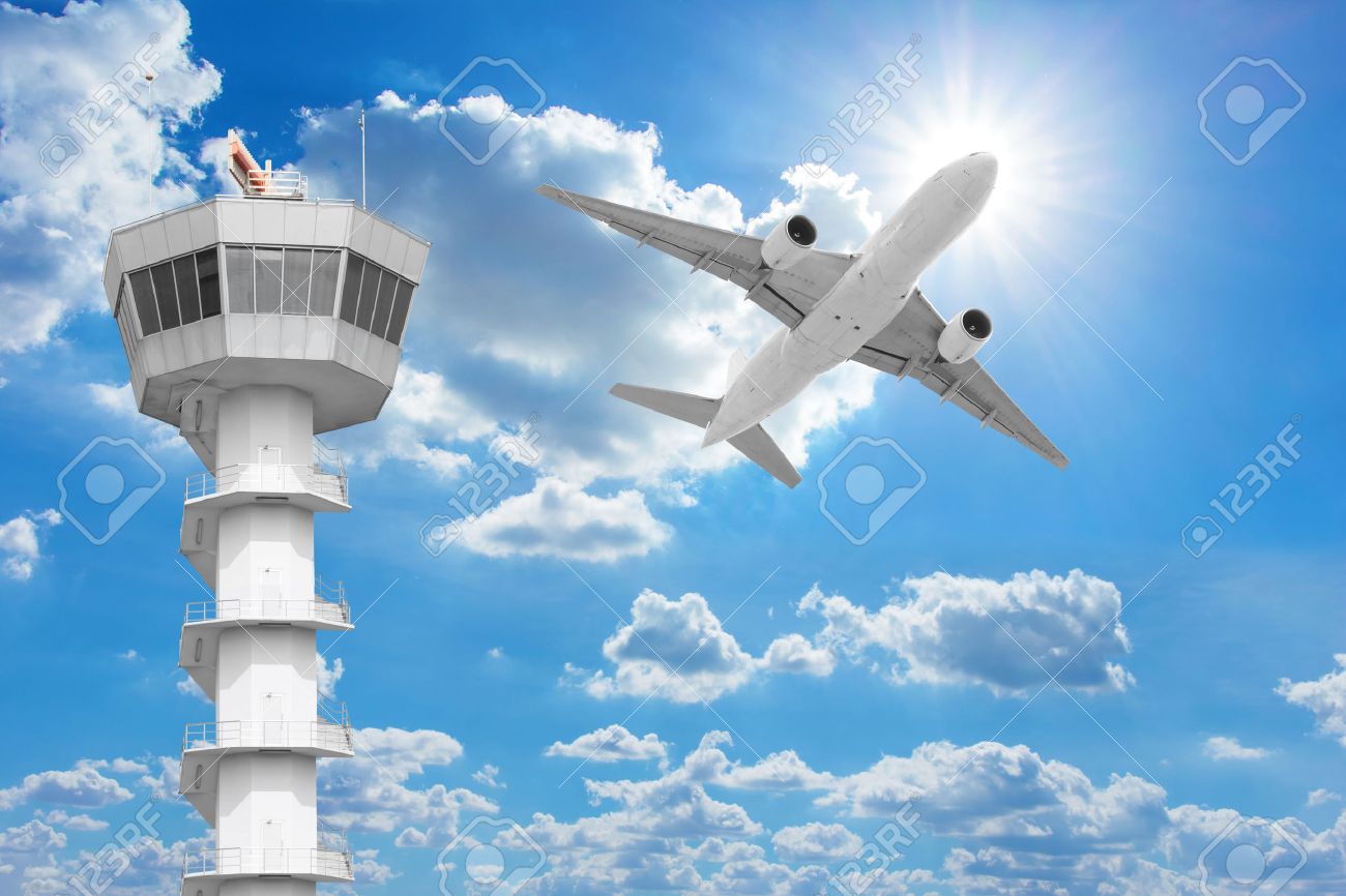 Passenger aircraft flying above air traffic control tower against blue sky - 66533480 Passenger aircraft flying above air traffic control tower against blue sky - 66533480