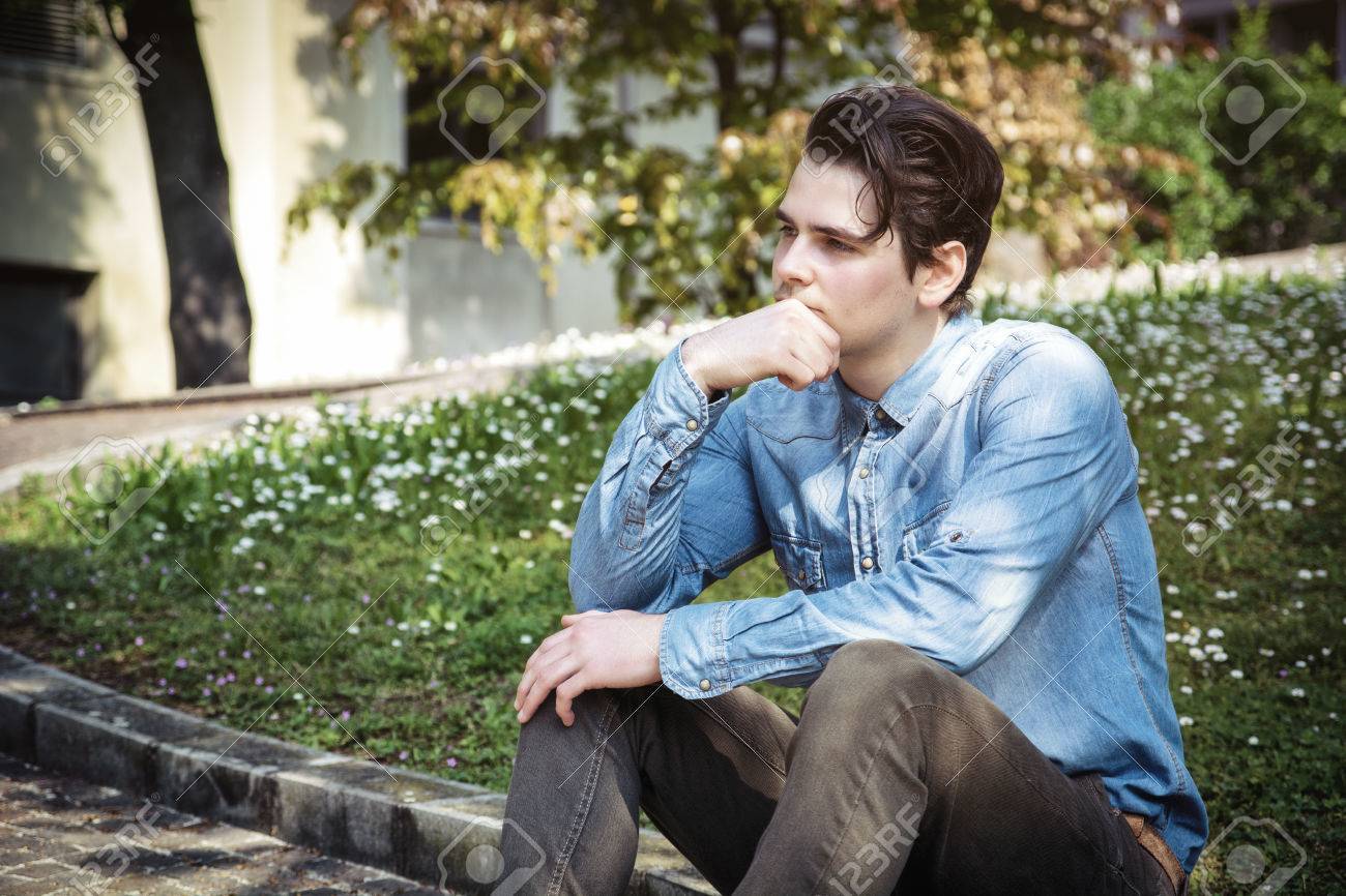 Vivre avec la nostalgie du passé : Bon ou mauvais ? 28333043-young-man-sitting-outdoors-in-public-park-with-hand-on-his-chin-looking-away-thinking