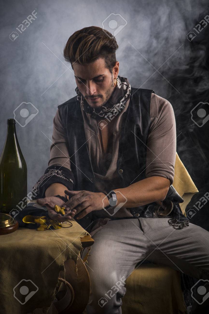 良い座っている海賊ファッション服装の若い男を見ていると手で金目たるを見て の写真素材 画像素材 Image