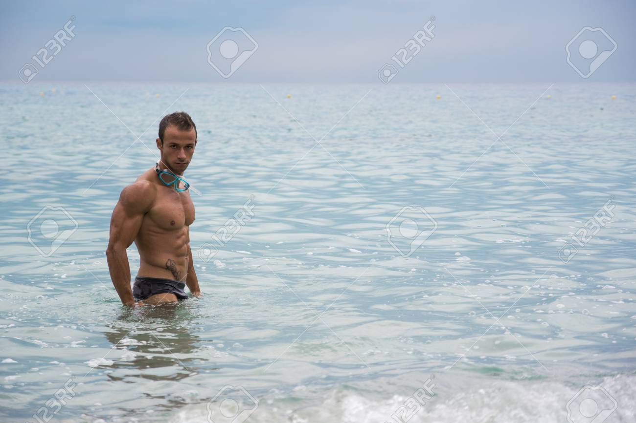 Beau Jeune Homme Musclé à La Plage Debout Dans La Mer De Profil Pose