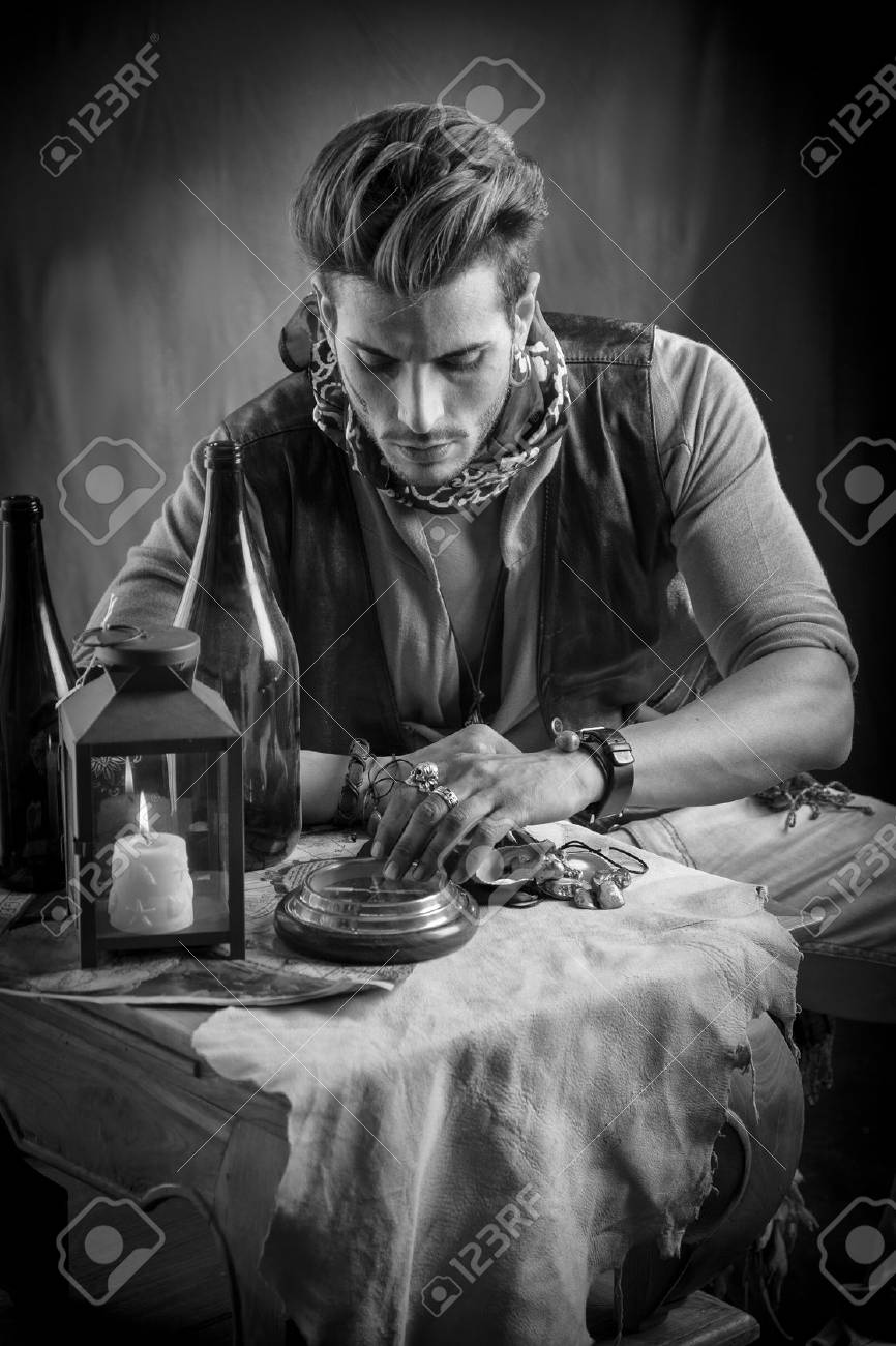 良い座っている海賊ファッション服装の若い男を見ていると手で金目たるを見て の写真素材 画像素材 Image