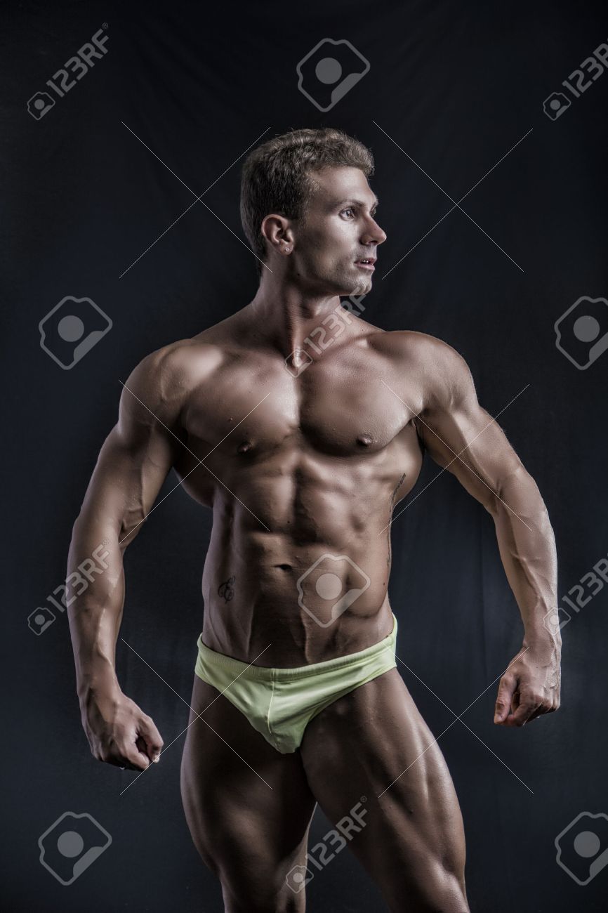 筋肉若いボディービルダー リラックスしたポーズの側にいます 下着を着て暗い背景に の写真素材 画像素材 Image