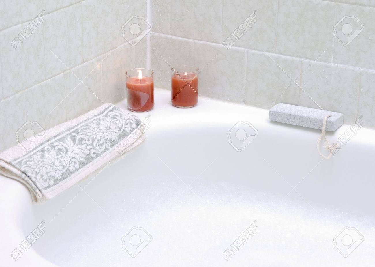 Bain moussant à la lumière des bougies allumées et de pierre ponce Bain moussant à la lumière des bougies allumées et de pierre ponce