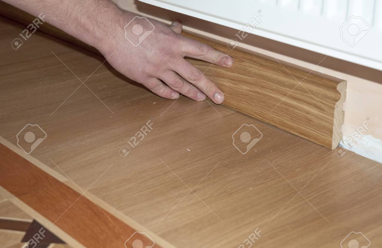 Skirting Board Architrave Repairman S Hands Installing Skirting Board Architrave Repairman S Hands Installing Oak Wooden Floor With Glue