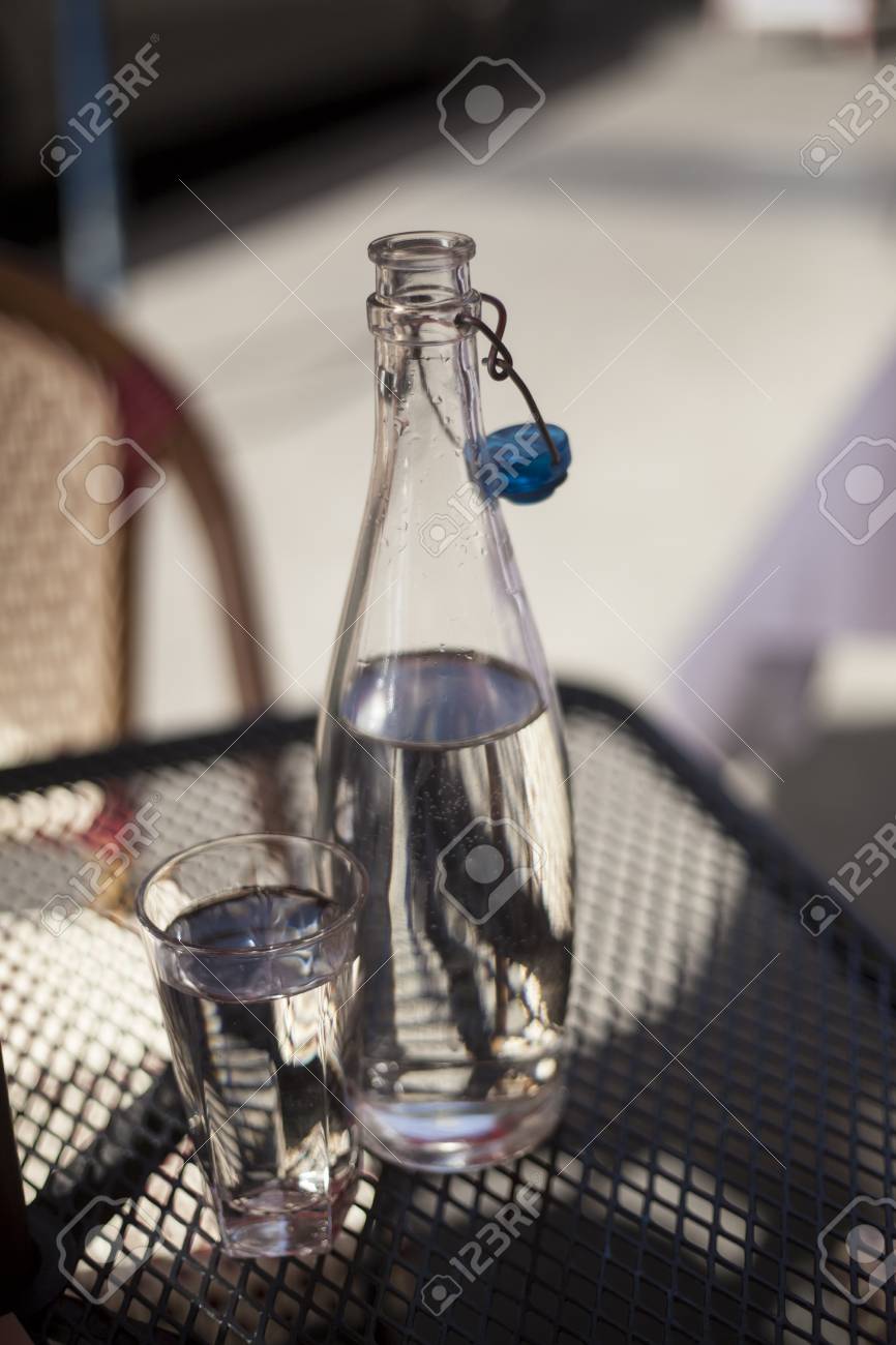 Immagini Stock Caraffa E Bicchiere Pieno D'acqua Seduto Su Bicchiere di vetro e la caraffa con acqua su un tavolo