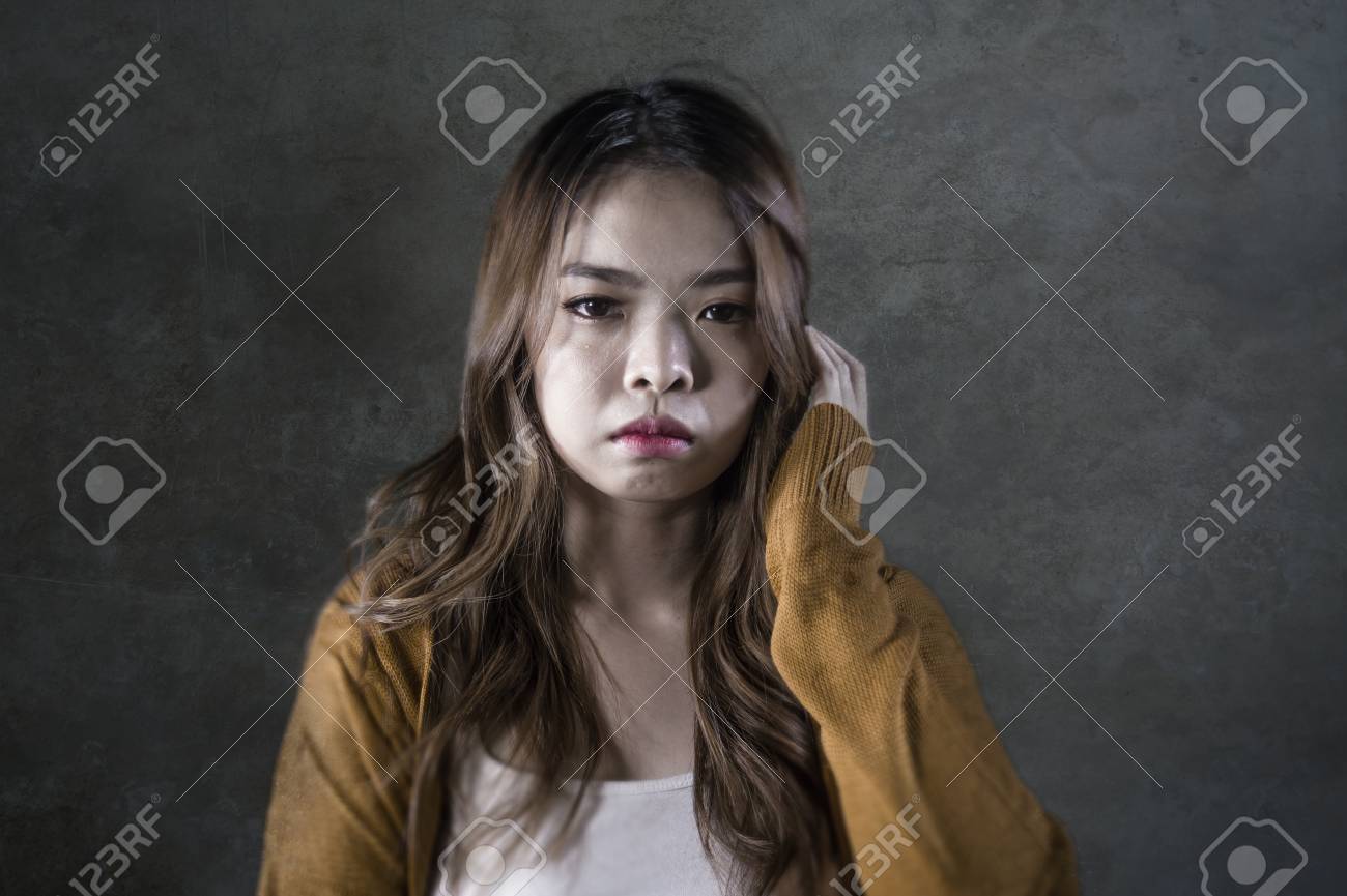 女　苦しむ　表情 うつ病に苦しむ痛みの顔の表情で孤立した暗い背景に苦悩と痛みを感じて落ち込んで無力感を感じている若い狂気の絶望的で悲しいアジアの韓国人女性の写真素材・画像素材  Image 114777717