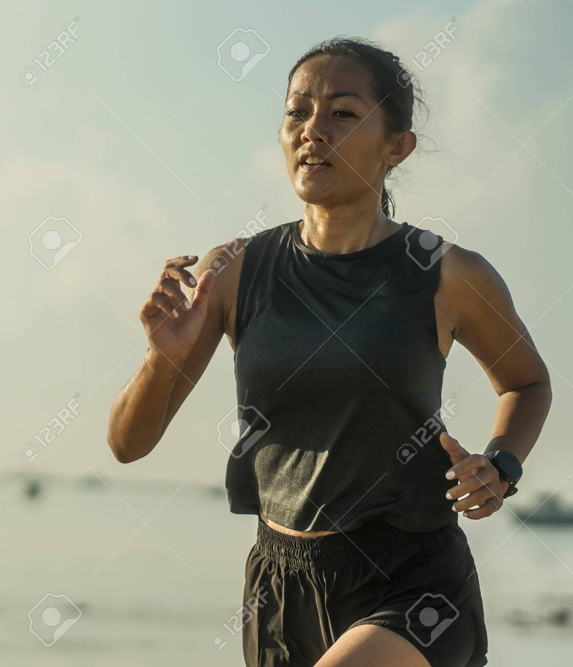 outdoors fitness portrait of young attractive and athletic Asian Indonesian woman in her 40s running on the beach doing intervals workout in athlete training concept and healthy lifestyle - 140318296 outdoors fitness portrait of young attractive and athletic Asian Indonesian woman in her 40s running on the beach doing intervals workout in athlete training concept and healthy lifestyle - 140318296
