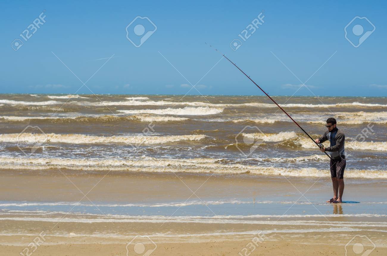 Young man fishing on beach, sport fishing. - 98185624 Young man fishing on beach, sport fishing. - 98185624