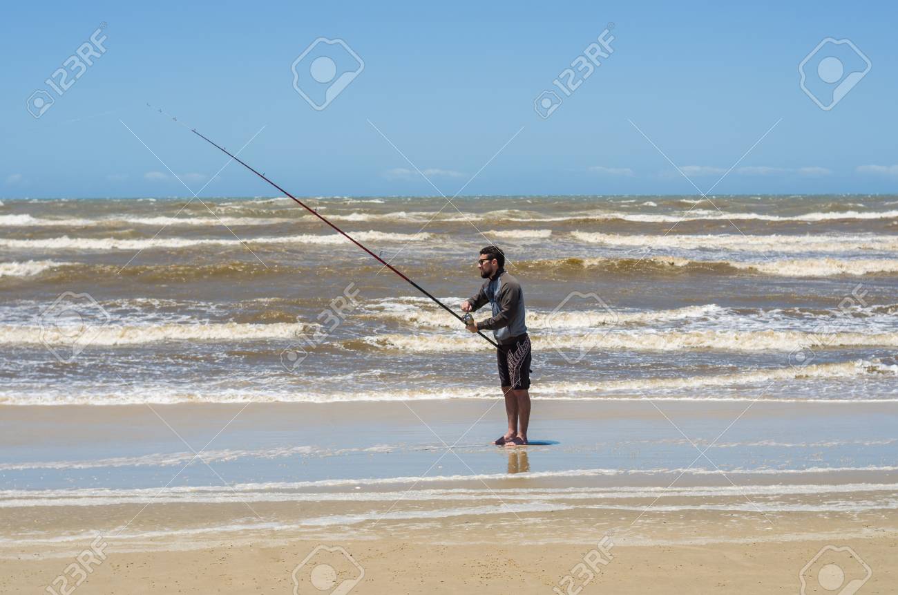 Young man fishing on beach, sport fishing. - 98185638 Young man fishing on beach, sport fishing. - 98185638