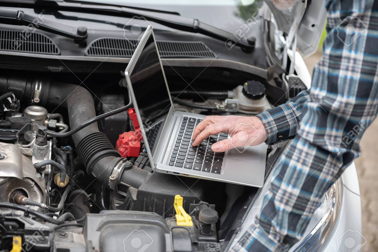 Car mechanic using laptop for checking car engine - 141985376 Car mechanic using laptop for checking car engine - 141985376