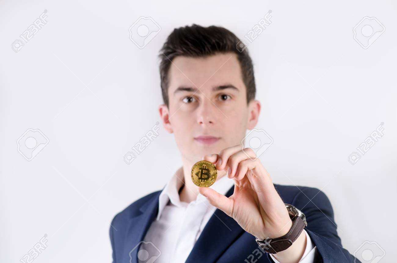 Young Business Man Holding A Bitcoin Coin. White Collar. Cryptocurrency  Symbol Of Bitcoin. Money And Investment Background. Young Business Man  Holding A Bitcoin Coin. White Collar. Cryptocurrency Symbol Of Bitcoin.  Money And