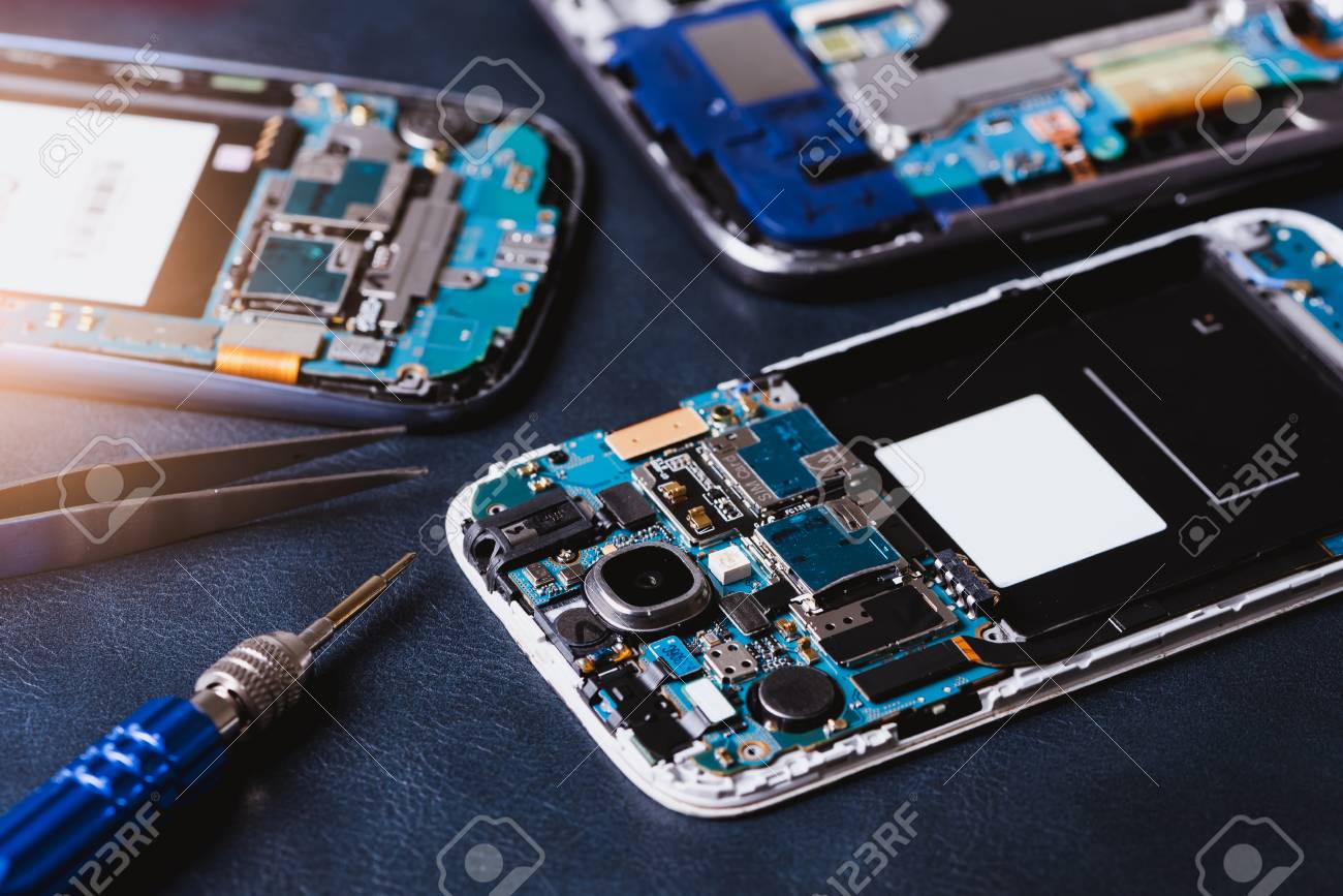 The inside of the smartphone's motherboard and tools lay on the back table. the concept of computer hardware, mobile phone, electronic, repairing, upgrade and technology. - 101380587 The inside of the smartphone's motherboard and tools lay on the back table. the concept of computer hardware, mobile phone, electronic, repairing, upgrade and technology. - 101380587