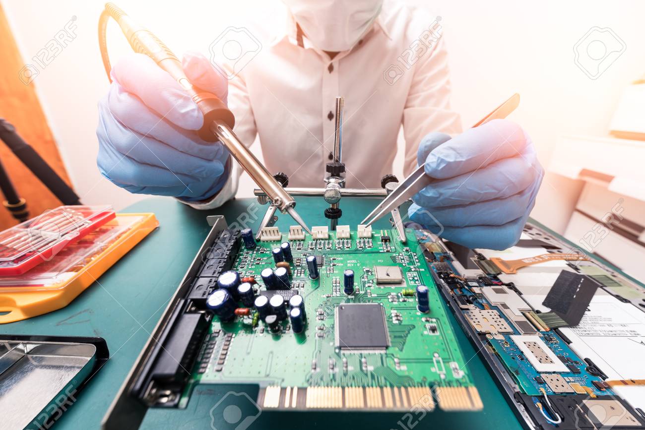 The asian technician repairing the motherboard by soldering in the lab. the concept of computer hardware, mobile phone, electronic, repairing, upgrade and technology. - 101445213 The asian technician repairing the motherboard by soldering in the lab. the concept of computer hardware, mobile phone, electronic, repairing, upgrade and technology. - 101445213