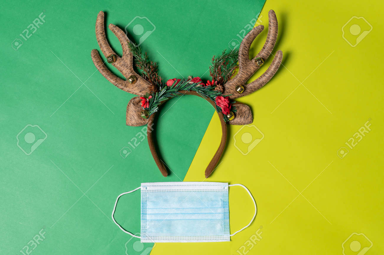 the Christmas props and the protective mask laying on the color backdrop. the concept of festival, pandemic, celebrating, coronavirus and Christmas - 159293597 the Christmas props and the protective mask laying on the color backdrop. the concept of festival, pandemic, celebrating, coronavirus and Christmas - 159293597