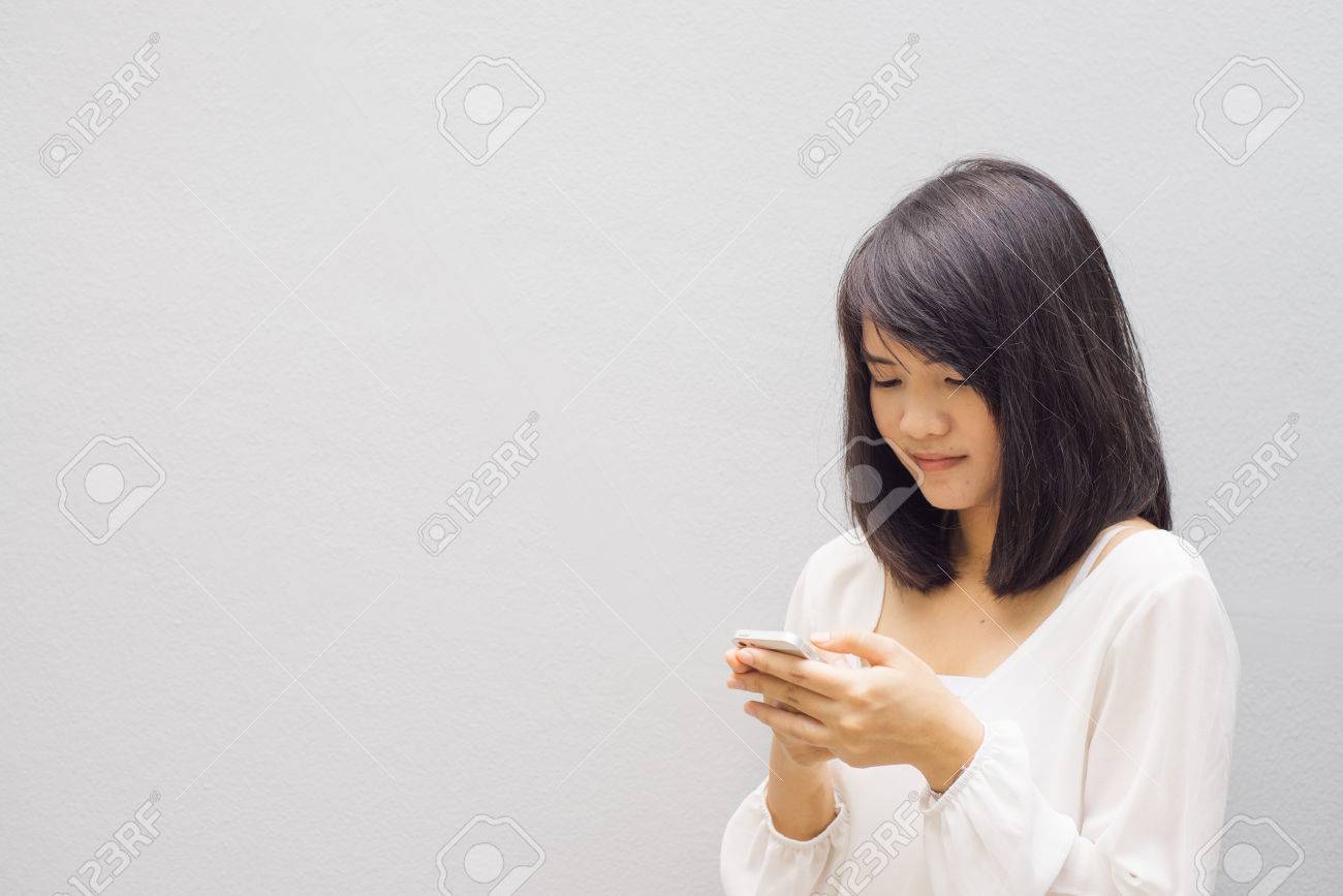 beautiful asian woman using cellphone, over concrete wall - 43655033 beautiful asian woman using cellphone, over concrete wall - 43655033