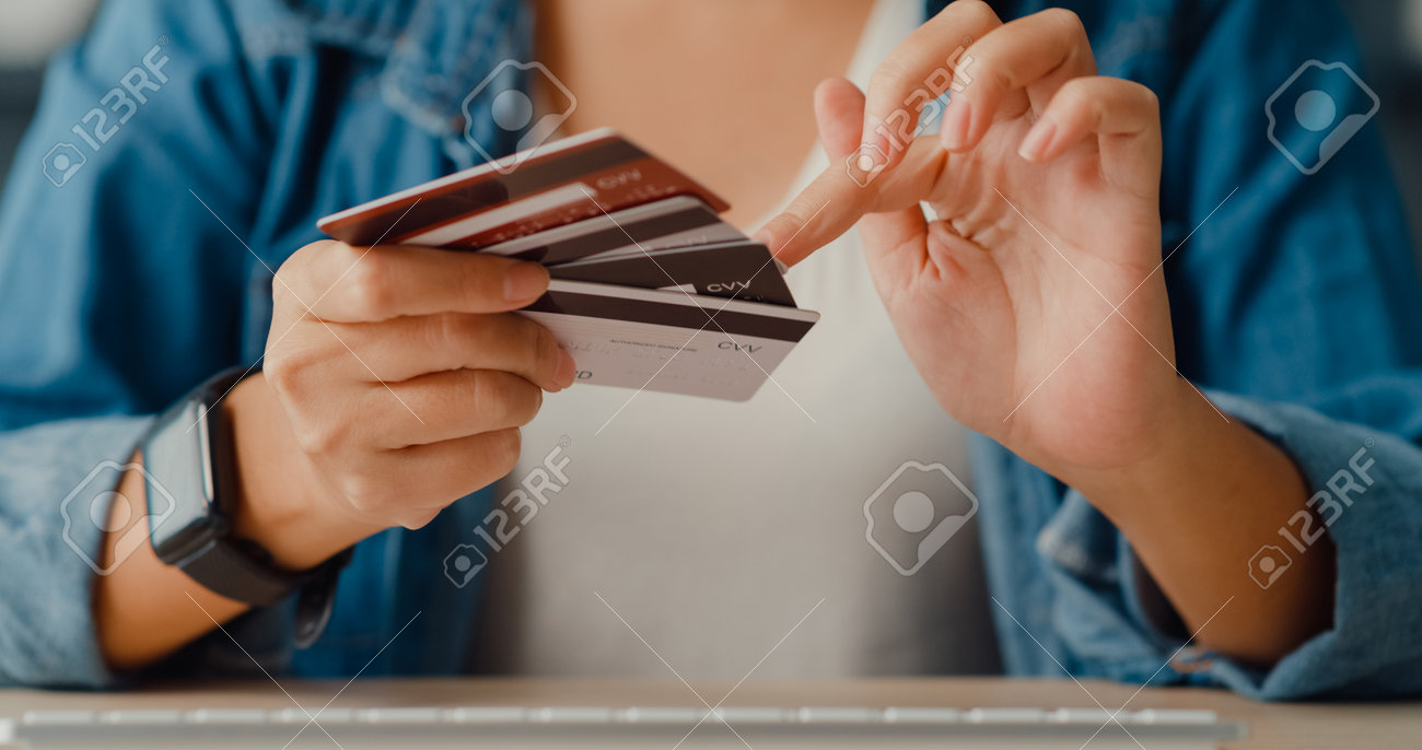 Young asia lady using computer order online shopping product and paying bill with credit card in living room interior. Stay at house, Self quarantine activity, Fun activity for coronavirus prevention. - 169422725 Young asia lady using computer order online shopping product and paying bill with credit card in living room interior. Stay at house, Self quarantine activity, Fun activity for coronavirus prevention. - 169422725
