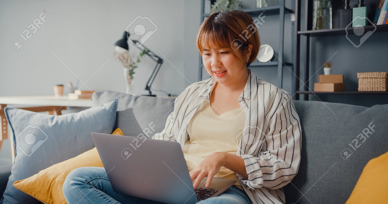 Freelance Asia lady casual wear using laptop online learning in living room at house. Working from home, remotely work, distance education, social distancing, quarantine for corona virus prevention. - 169422745 Freelance Asia lady casual wear using laptop online learning in living room at house. Working from home, remotely work, distance education, social distancing, quarantine for corona virus prevention. - 169422745