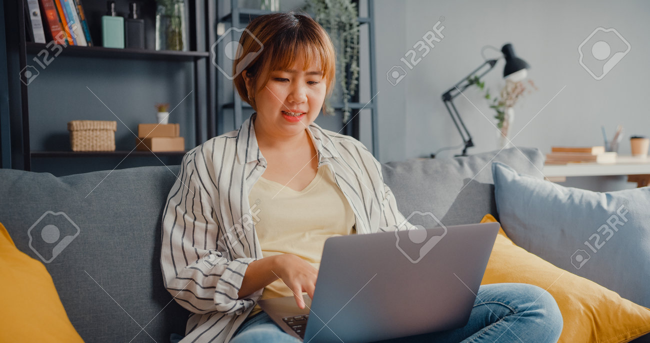 Freelance Asia lady casual wear using laptop online learning in living room at house. Working from home, remotely work, distance education, social distancing, quarantine for corona virus prevention. - 169422855 Freelance Asia lady casual wear using laptop online learning in living room at house. Working from home, remotely work, distance education, social distancing, quarantine for corona virus prevention. - 169422855
