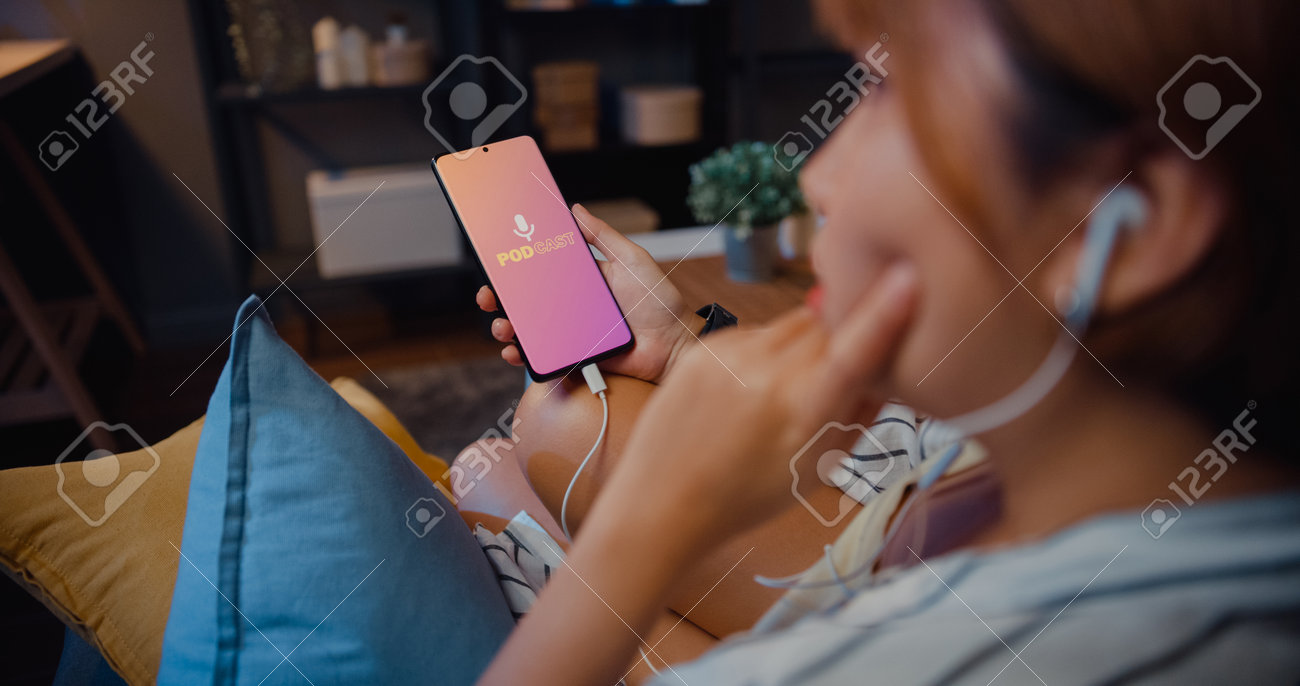 Young attractive Asia lady wear headphones using phone listen digital music podcast online channel sit on sofa in living room at house night. Social distancing, quarantine for coronavirus prevention. - 169422875 Young attractive Asia lady wear headphones using phone listen digital music podcast online channel sit on sofa in living room at house night. Social distancing, quarantine for coronavirus prevention. - 169422875
