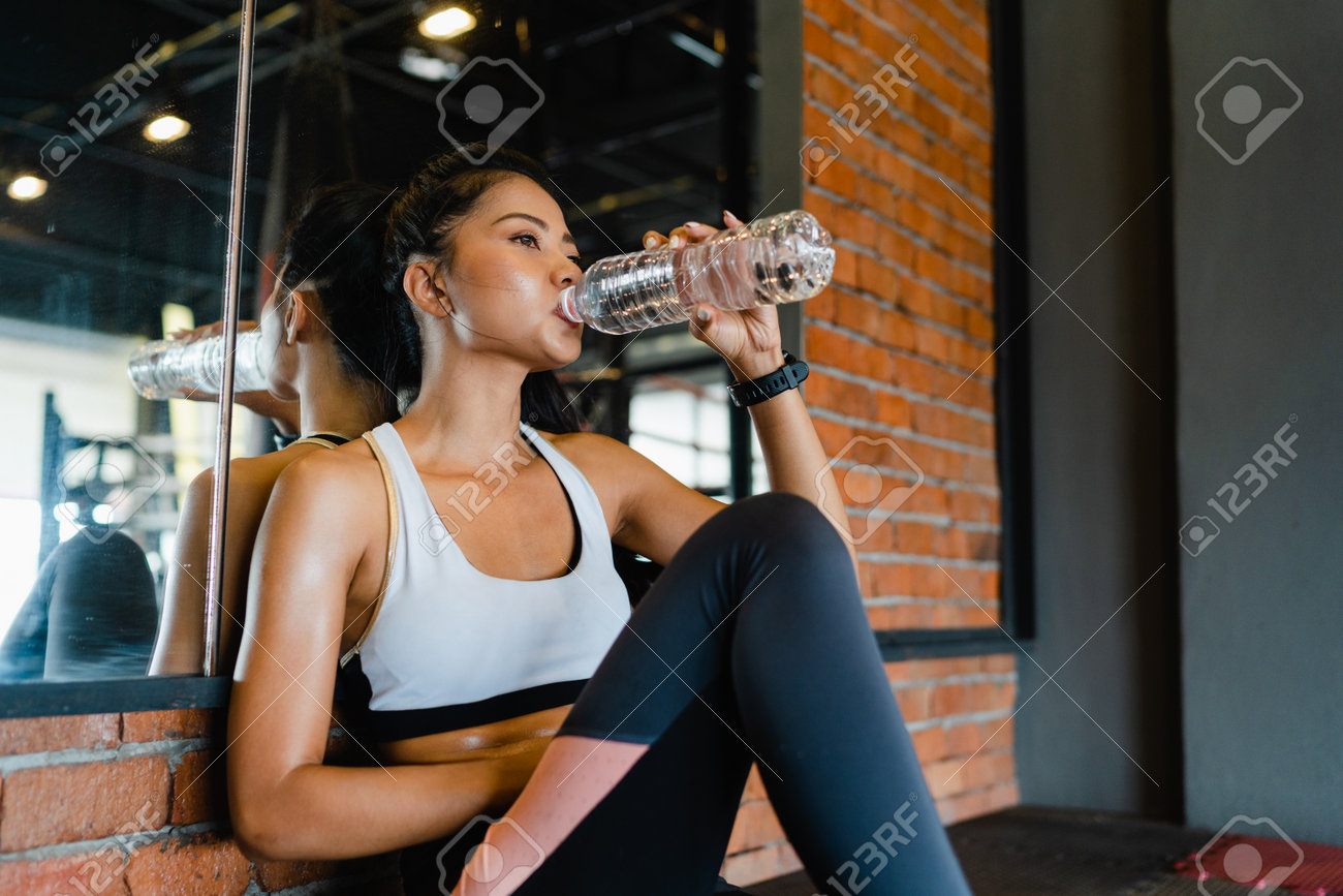 Beautiful young Asia lady exercise drinking water after fat burning workout in fitness class. Athlete with six pack, Sportswoman recreational activity, functional training, healthy lifestyle concept. - 169422986 Beautiful young Asia lady exercise drinking water after fat burning workout in fitness class. Athlete with six pack, Sportswoman recreational activity, functional training, healthy lifestyle concept. - 169422986