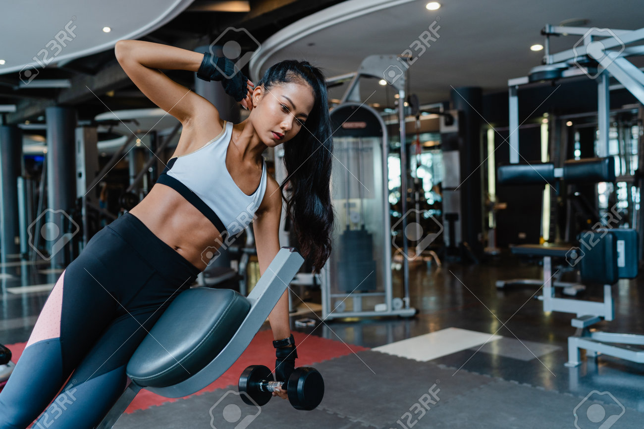 Beautiful young Asia lady exercise doing lifting barbell fat burning workout in fitness class. Athlete with six pack, Sportswoman recreational activity, functional training, healthy lifestyle concept. - 169422993 Beautiful young Asia lady exercise doing lifting barbell fat burning workout in fitness class. Athlete with six pack, Sportswoman recreational activity, functional training, healthy lifestyle concept. - 169422993