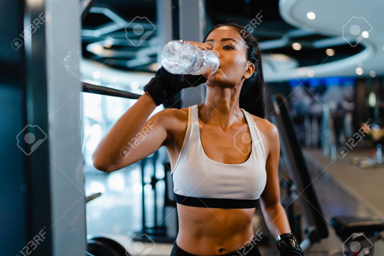 Beautiful young Asia lady exercise drinking water after fat burning workout in fitness class. Athlete with six pack, Sportswoman recreational activity, functional training, healthy lifestyle concept. - 169423002 Beautiful young Asia lady exercise drinking water after fat burning workout in fitness class. Athlete with six pack, Sportswoman recreational activity, functional training, healthy lifestyle concept. - 169423002