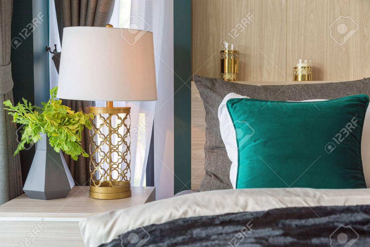 A Gold Luxury Lamp On A Beige Table Beside The Bed With A Frame