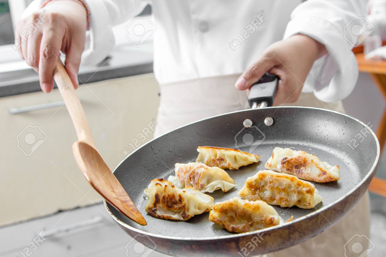 chef making gyoza japanese dumplings in frying pan stock photo