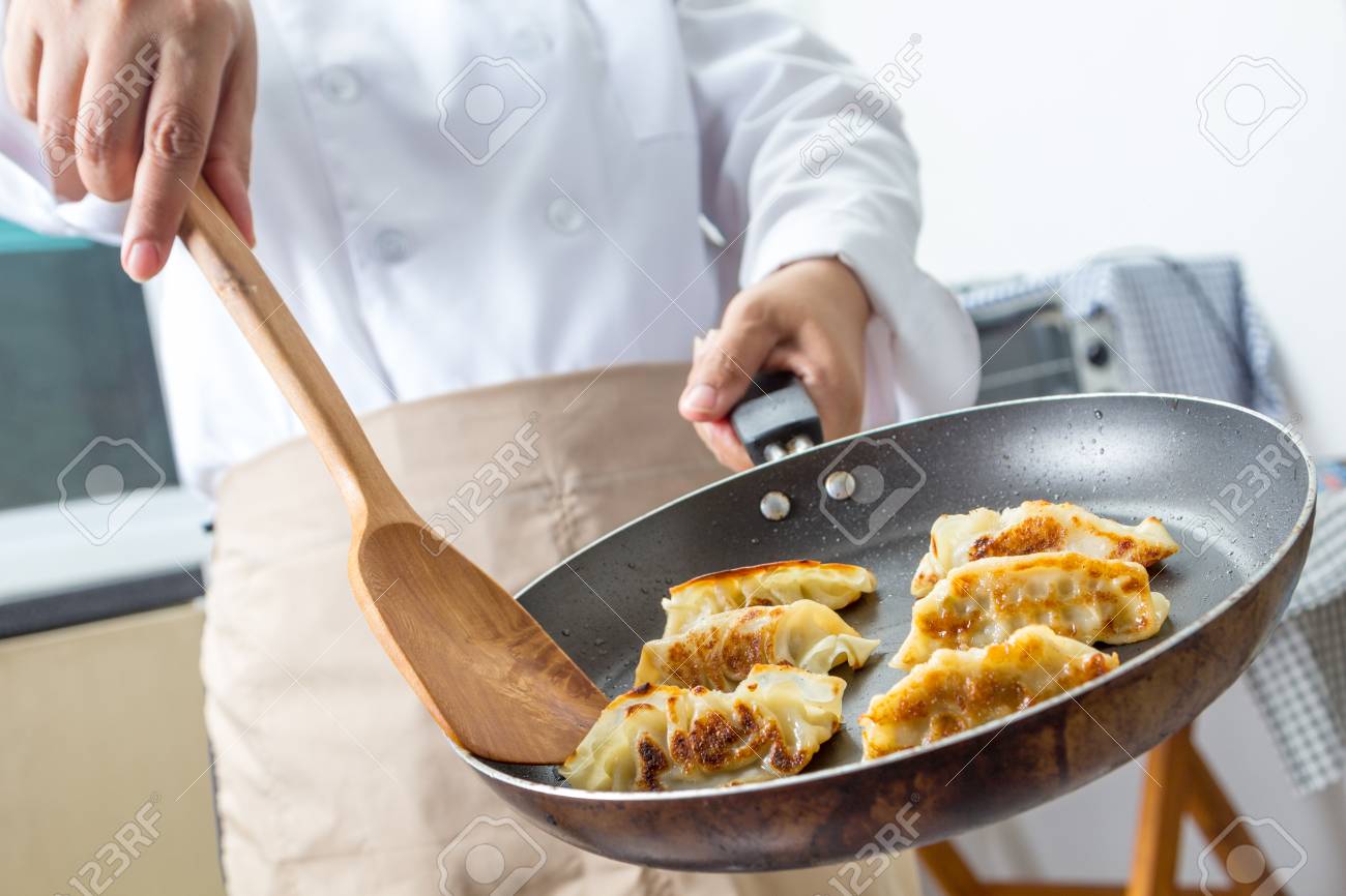 chef making gyoza japanese dumplings in frying pan stock photo