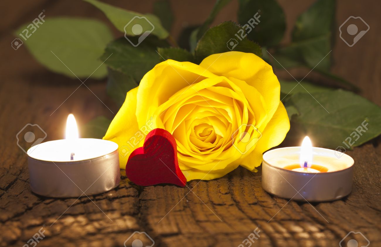 Una rosa gialla fiore e due luci di tè con un cuore rosso in legno ...