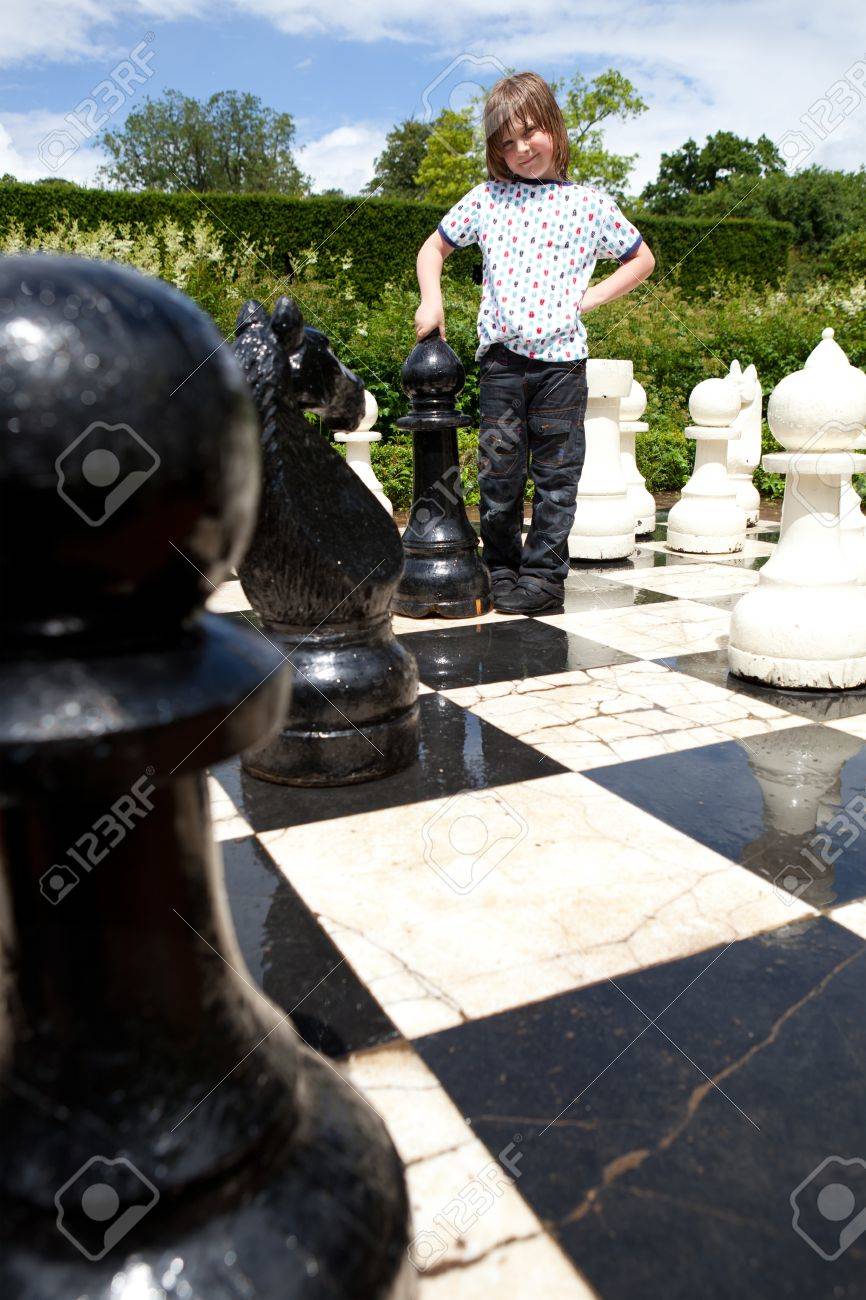 巨大なチェスの駒でチェス ゲーム 黒と白のボード上の子供が戦略的な屋外ゲーム の写真素材 画像素材 Image