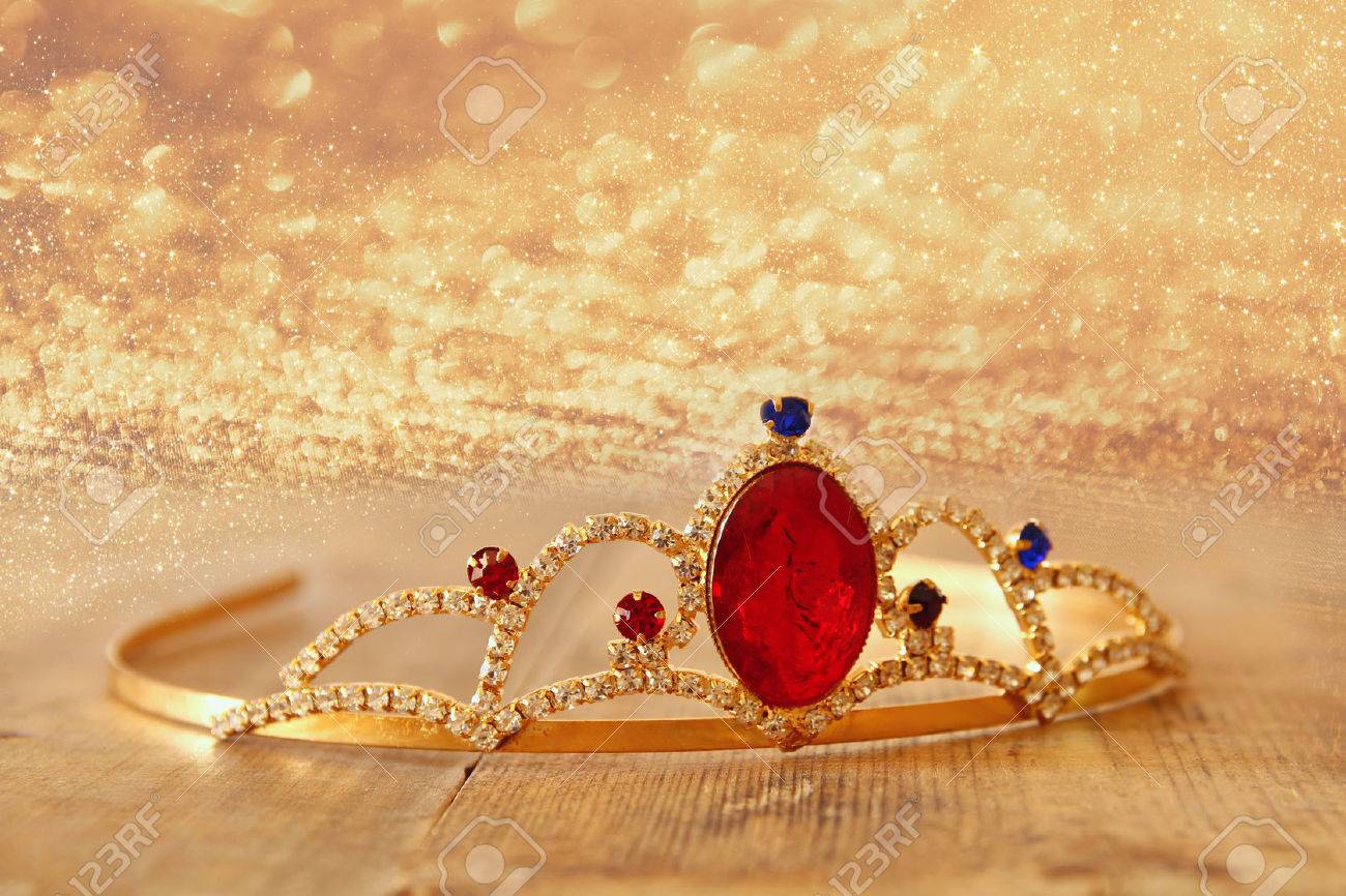 image of gold princes crown on wooden table and glitter background