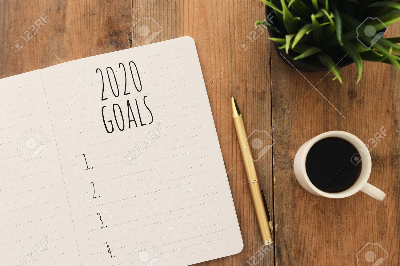 Business concept of top view 2020 goals list with notebook, cup of coffee over wooden desk - 132602091 Business concept of top view 2020 goals list with notebook, cup of coffee over wooden desk - 132602091