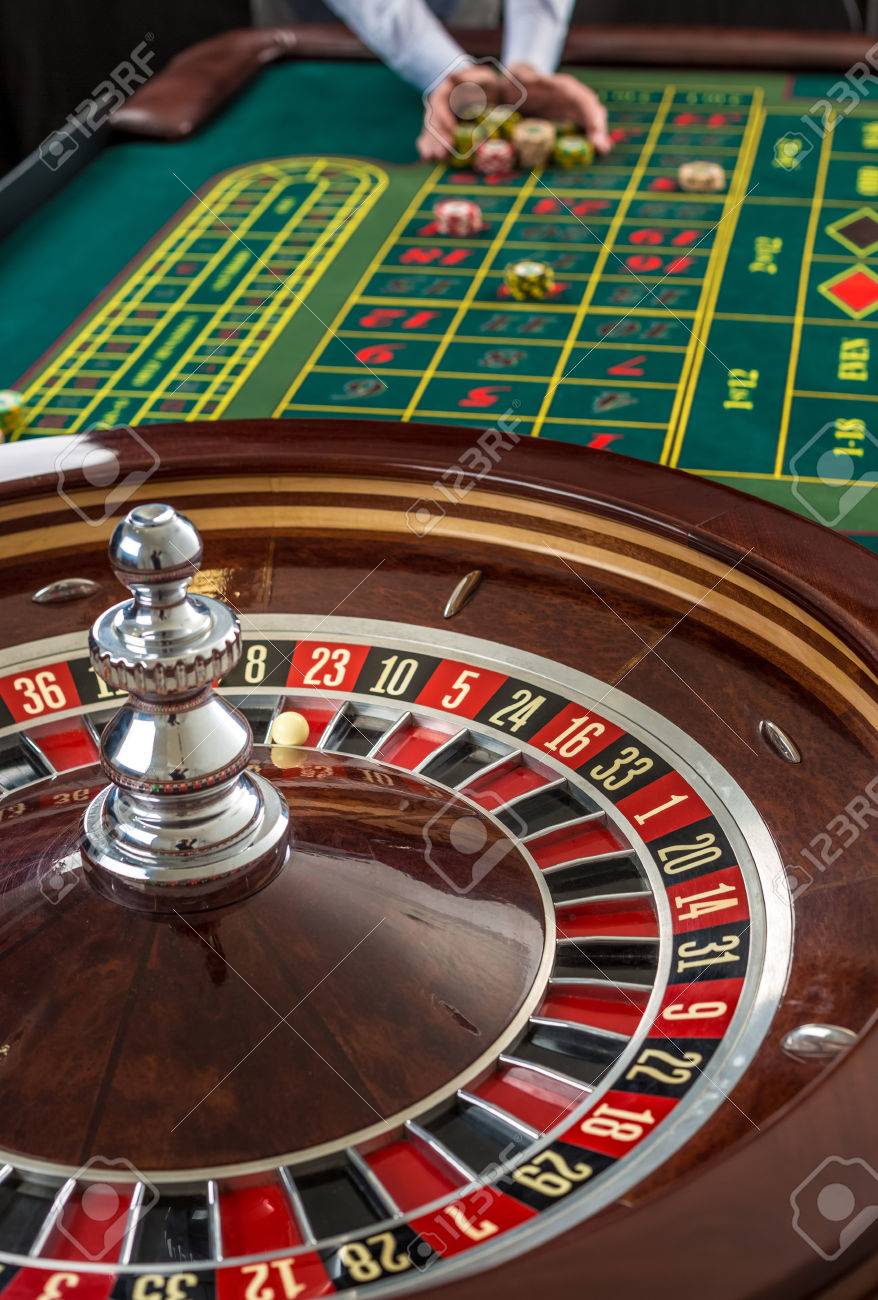 Nahaufnahme von Roulette und Haufen von Spielmarken auf einem grünen Tisch im Casino. Man Hand über Casino Chips auf Roulette Tisch Nahaufnahme von Roulette und Haufen von Spielmarken auf einem grünen Tisch im Casino. Man Hand über Casino Chips auf Roulette Tisch