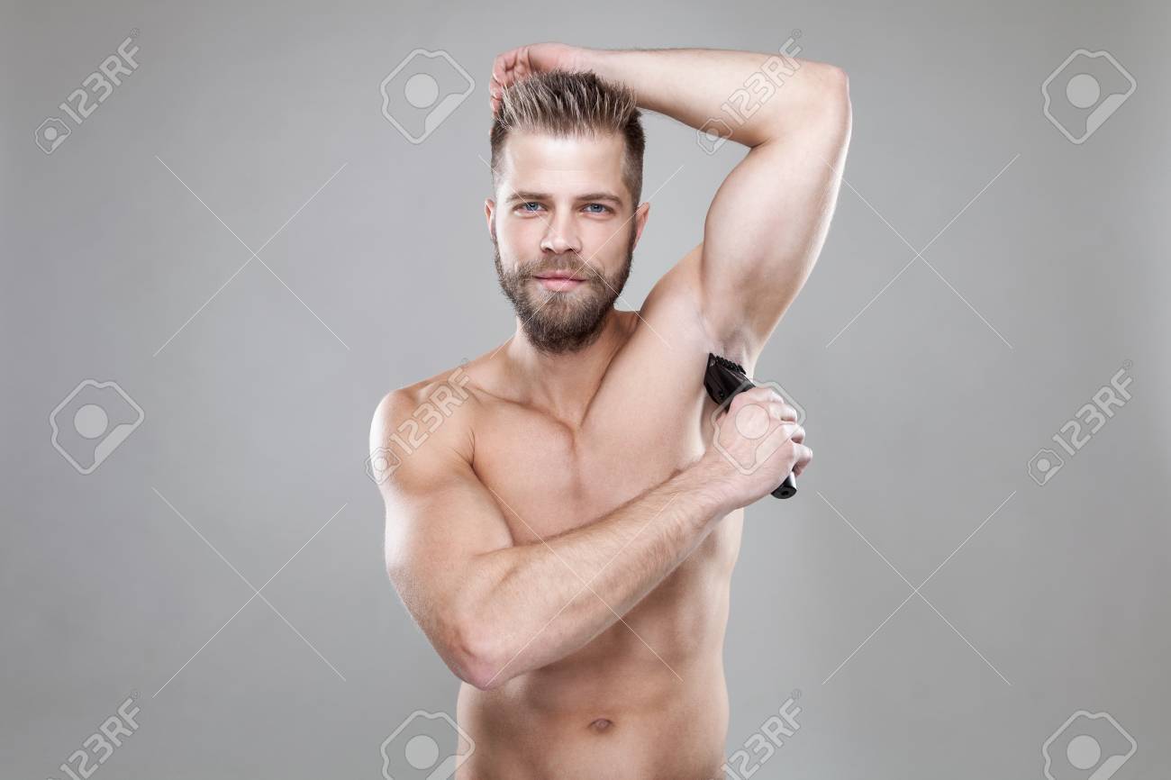 Handsome Young Bearded Man With A Trimmer Shaving Off Body Hair