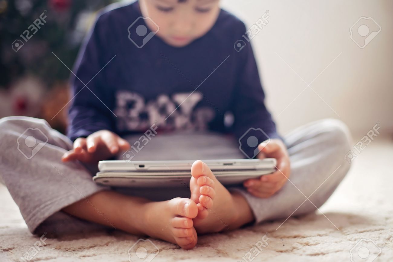 Cute Little Boys Feet Boy Playing On Tablet In Front Of A Christmas Tree Stock Cute Little Boys Feet Boy Playing On Tablet In Front Of A Christmas Tree Stock