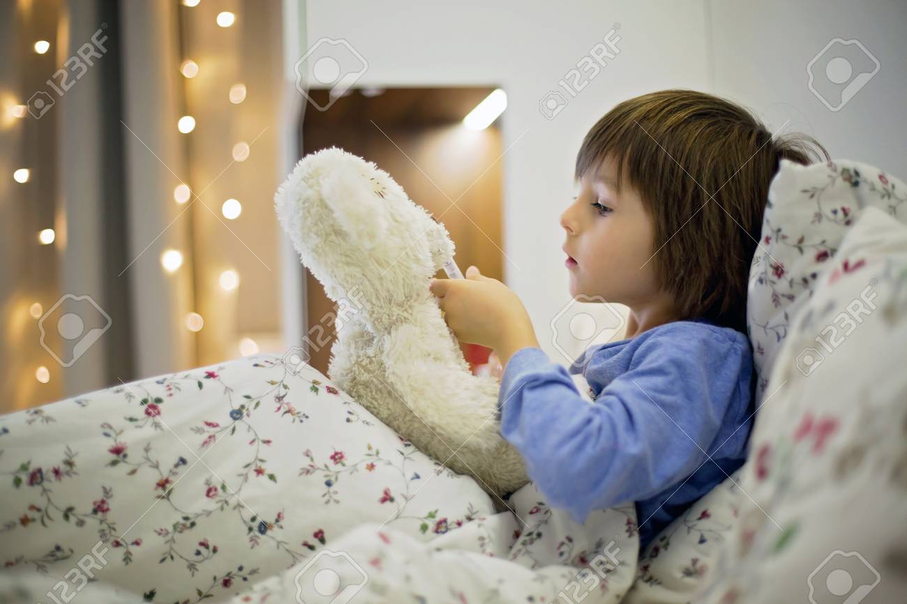 かわいい病気の子供 少年 クマのぬいぐるみで遊んでベッドでの滞在は彼を与える医学と発熱をチェック の写真素材 画像素材 Image