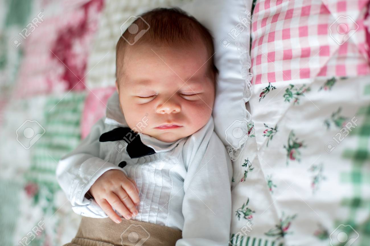 美しい小さな新生児の男の子は 小さな紳士の服を着て ベッドで眠って 彼の隣にかわいいおもちゃ の写真素材 画像素材 Image