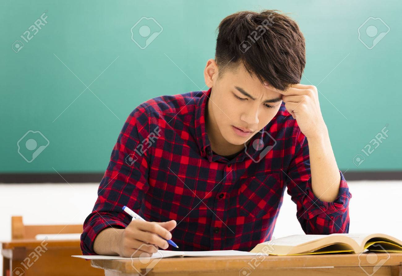 Stressed student studying for exam in classroom - 52000319 Stressed student studying for exam in classroom - 52000319