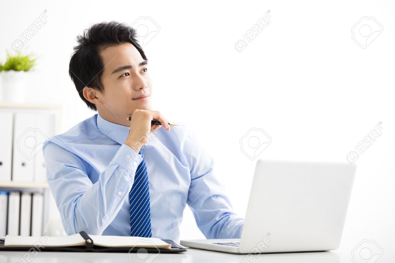 smiling young businessman working on laptop and thinking - 59965448 smiling young businessman working on laptop and thinking - 59965448