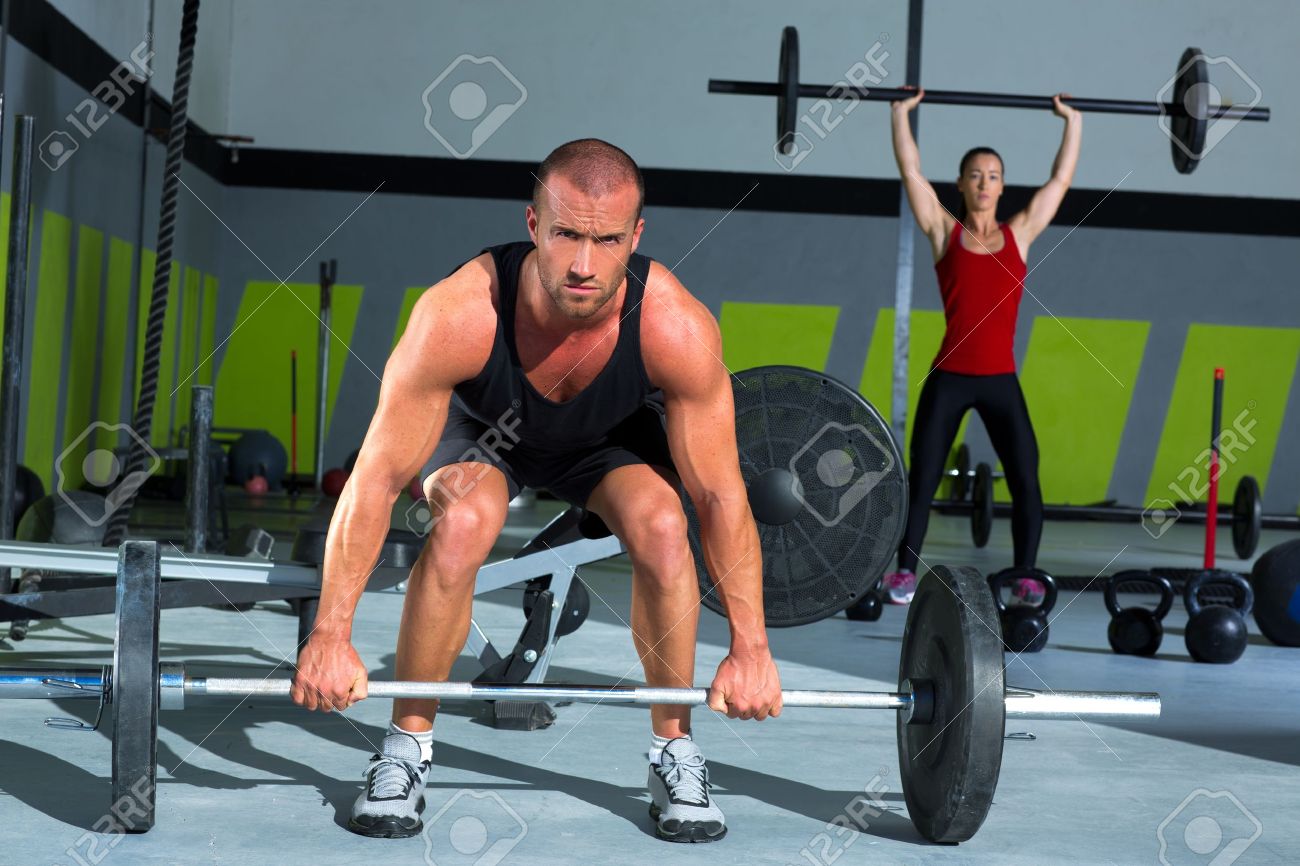 gym man and woman with weight lifting bar workout in crossfit