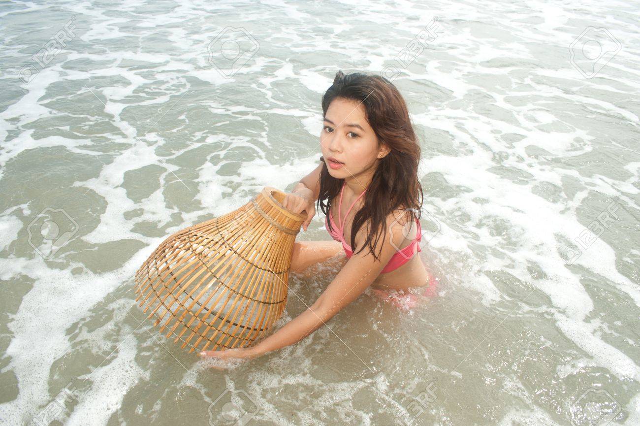 浅い水の中の魚を捕るための小屋のようなトラップを持つかなりアジア女性 の写真素材 画像素材 Image