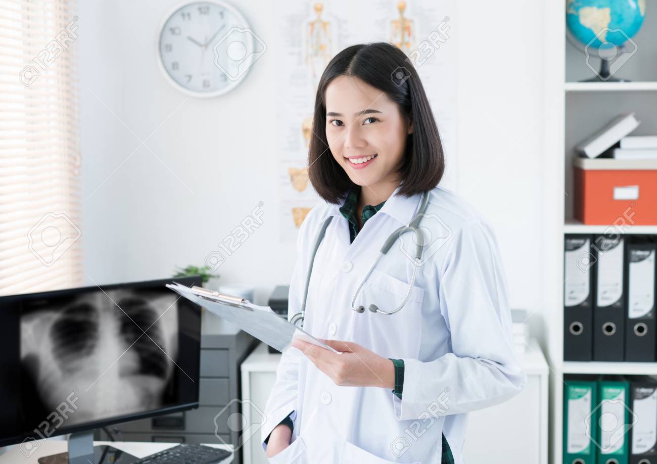 The doctor is sitting in the room to see the patient. She is opening x-ray effects. - 103248835 The doctor is sitting in the room to see the patient. She is opening x-ray effects. - 103248835