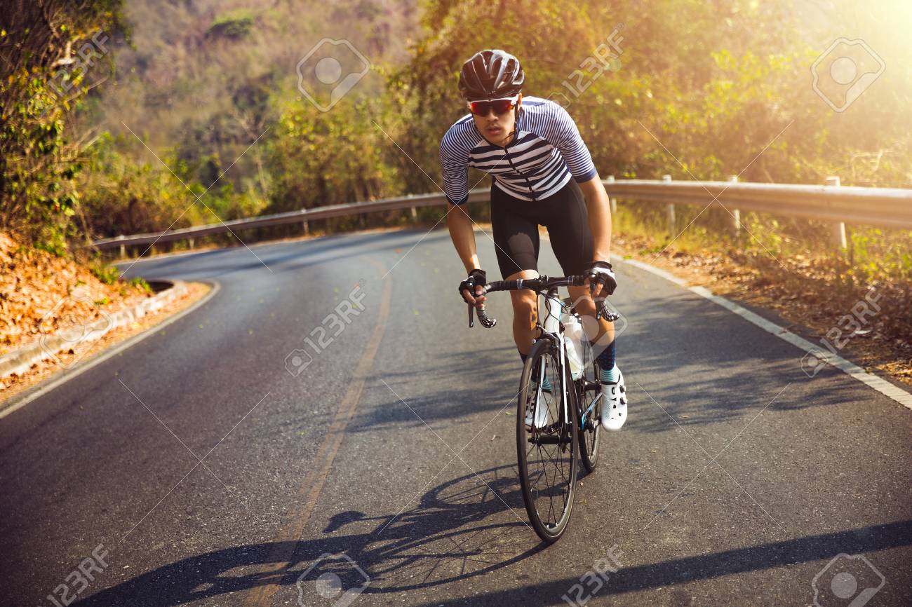 Asian man cycling road bike in the morning.He is on a forest road. - 120465291 Asian man cycling road bike in the morning.He is on a forest road. - 120465291